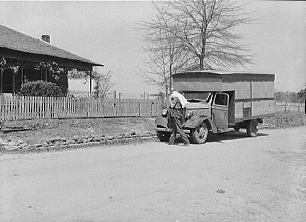 A "rolling store" salesman carrying sack of flour into rural home. Coffee County, Alabama