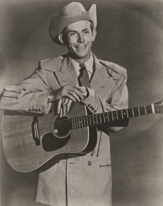 Hank_Williams_wearing_a_houndstooth_jacket_and_holding_a_guitar