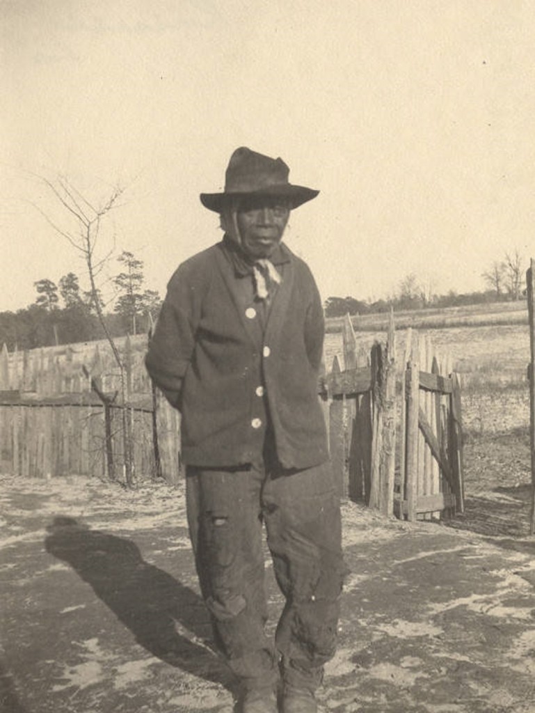 African American man standing in front of a picket fence in Crawford, Alabama Q5577 The same man is in image Q5586.