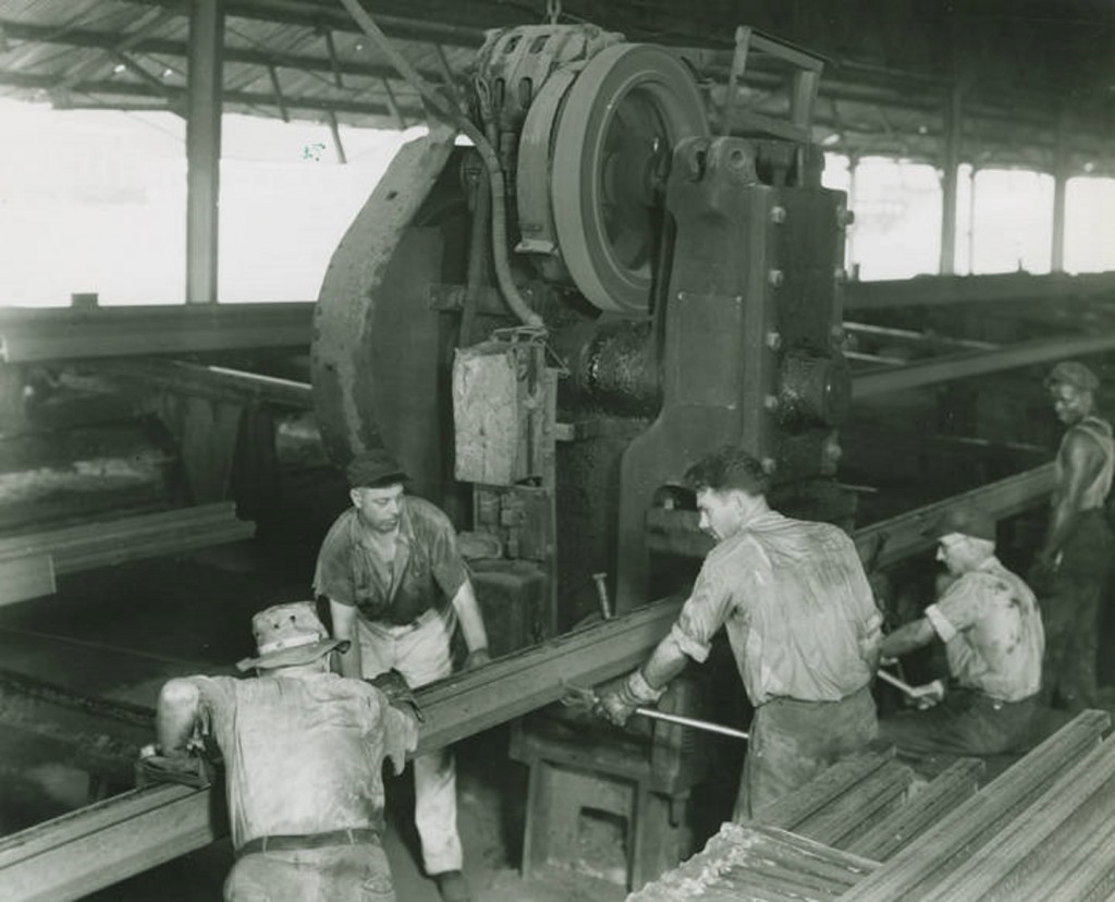 Here workmen at the Ensley Rail Mill straighten a steel rail, which presently will become a portion of track for some southern railroad. ca. 1949 photographer Roy T. Carter, Sr. Birmingham News-Age-Herald Q46227 