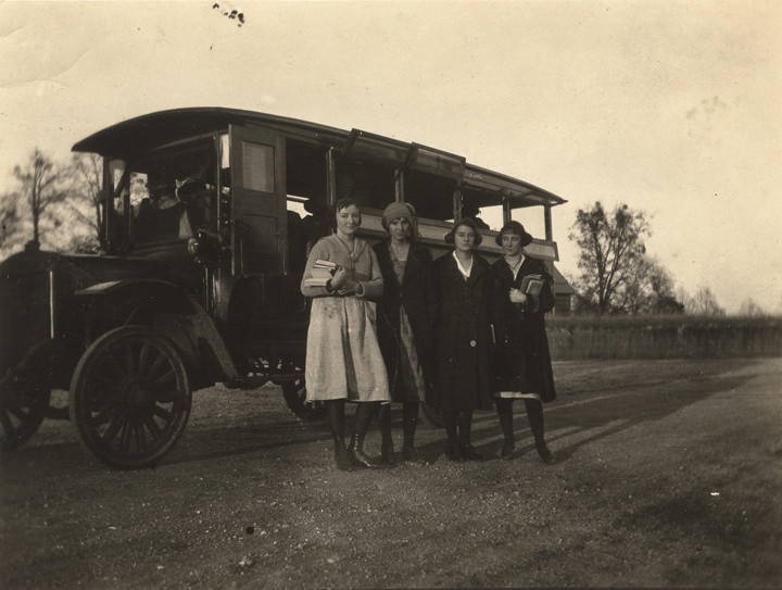 Getting off the bus at their house twelve miles from Ramer High School where they go every day – four female students in Montgomery County, Alabama standing by a school bus ca. 1920 Q3898