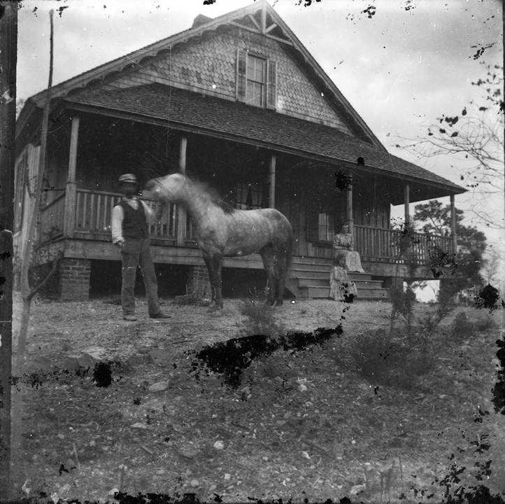 Man_standing_with_a_horse_in_the_front_yard_of_a_house_in_Montevallo_Alabama