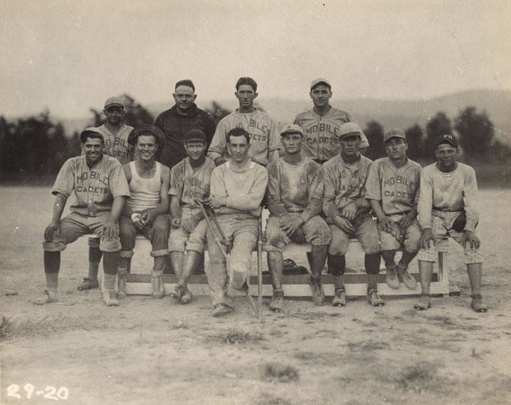 Men on a baseball team at the Air Corps base at Roberts Field in Birmingham, Alabama. ca. 1920s – Most of the men in the group are wearing shirts that say, Mobile Cadets.