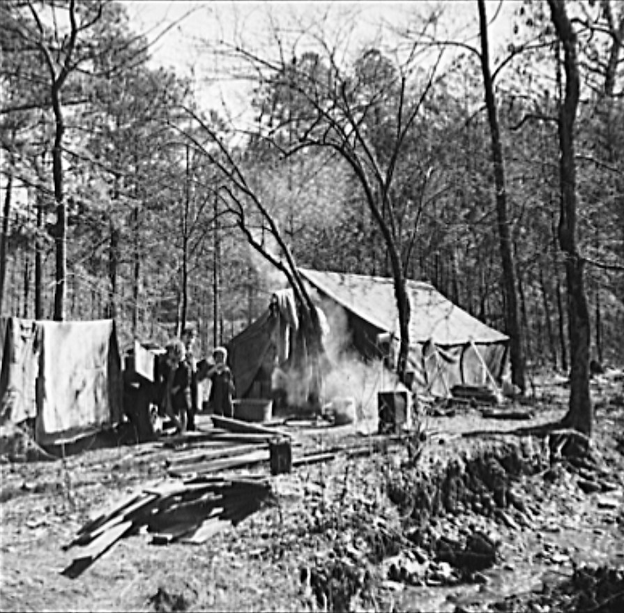 Tent occupied by sharecropper family now living in a migrant camp near Birmingham, Alabama. Note water supply at right (Library of Congress)