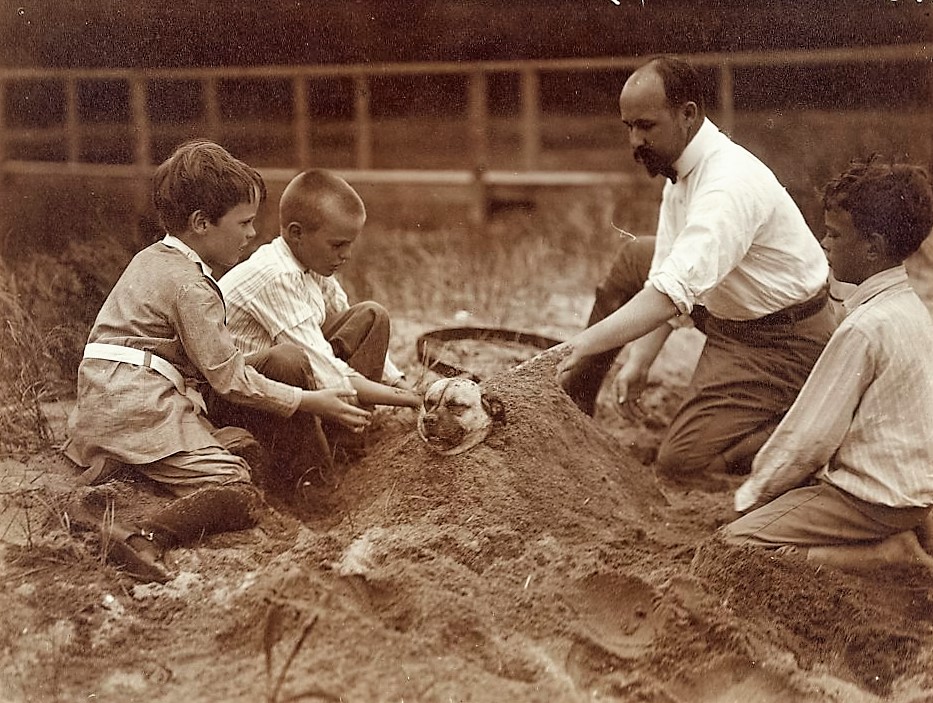 Photograph showing Quentin, Archie, and Nicholas Roosevelt, with Walter Russell, burying a dog in the sand at Sagamore Hill (2)